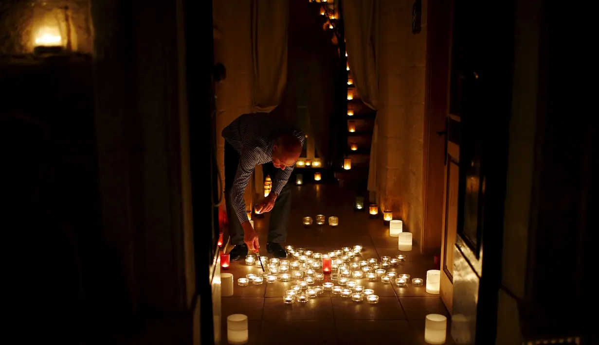 Seorang pria sedang menyalakan lilin yang ia hias didalam rumahnya untuk ikut memeriahkan festival Birgu di Malta, Sabtu (10/10/2015). Festival ini merupakan acara tradisional yang digelar setiap tahun. REUTERS/Darrin Zammit)