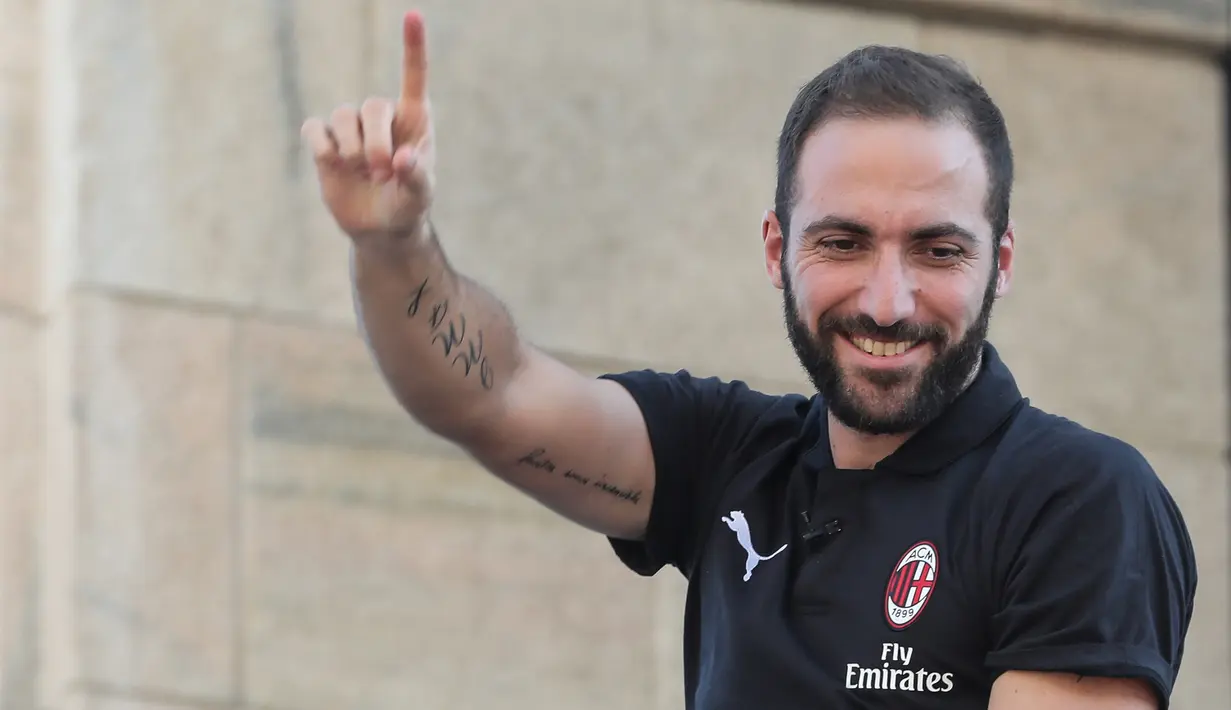Pemain baru AC Milan, Gonzalo Higuain menyapa suporter dari balkon di alun-alun pusat Milan Piazza Duomo (3/8). AC Milan telah mendatangkan lima pemain baru pada bursa transfer musim panas tahun ini. (AFP Photo/Stringer)
