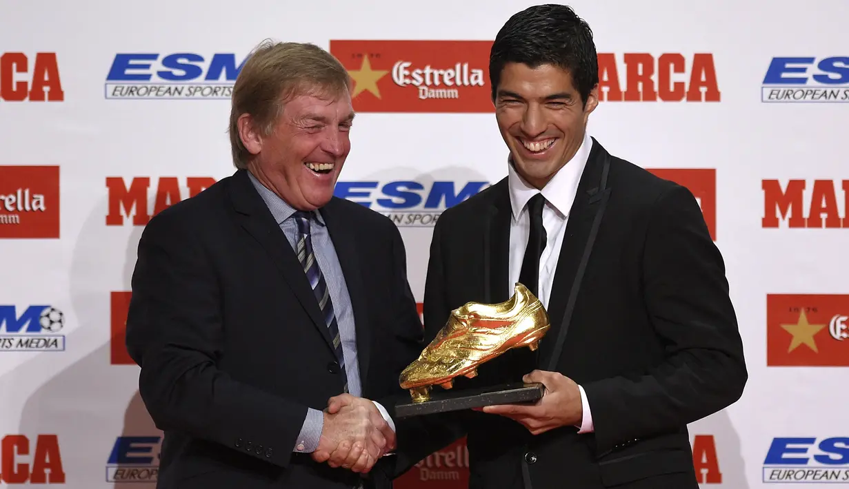 Eks pemain Liverpool, Kenny Dalglish (kiri) menyalami striker Barcelona, Luis Suarez yang meraih trofi Sepatu Emas Eropa saat membela Liverpool, di Barcelona (15/10/2014). Luis Suarez merebut trofi Sepatu Emas Eropa edisi 2014 setelah mencetak total 31 gol bagi Liverpool di Liga Inggris musim 2013/2014, bersanding dengan Cristiano Ronaldo (Real Madrid). Setelah hijrah ke Barcelona pada 2014/2015, Luis Suarez merebut Sepatu Emas Eropa pada musim 2015/2016. (AFP/Lluis Gene)