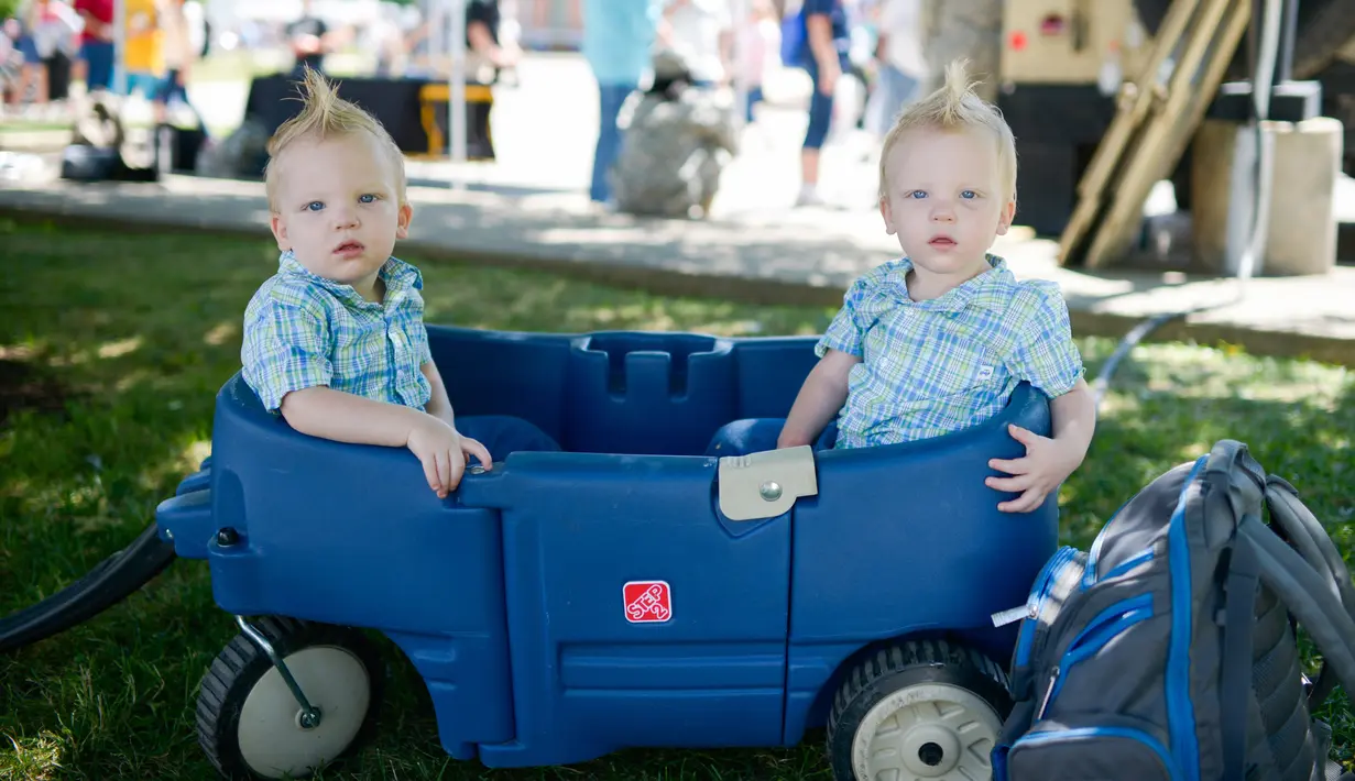 Pasangan kembar yang berusia 20 bulan dari Cleveland, Noah dan Owen Jury duduk dimobil mainan saat Festival Twins Days tahunan ke-42 di Twinsburg, Ohio (5/8). Festival ini mengumpulkan orang-orang yang memiliki kembaran. (AFP Photo/Dustin Franz)
