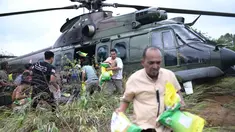 Para penyintas banjir membawa barang-barang bantuan yang didistribusikan oleh helikopter TNI AU di Aceh Tengah, Sabtu 6 Desember 2025. Meski menghadapi kendala putusnya akses darat akibat kerusakan infrastruktur parah, penyaluran bantuan banjir di Aceh Tengah terus berlangsung. (AP Photo/Reza Saifullah)