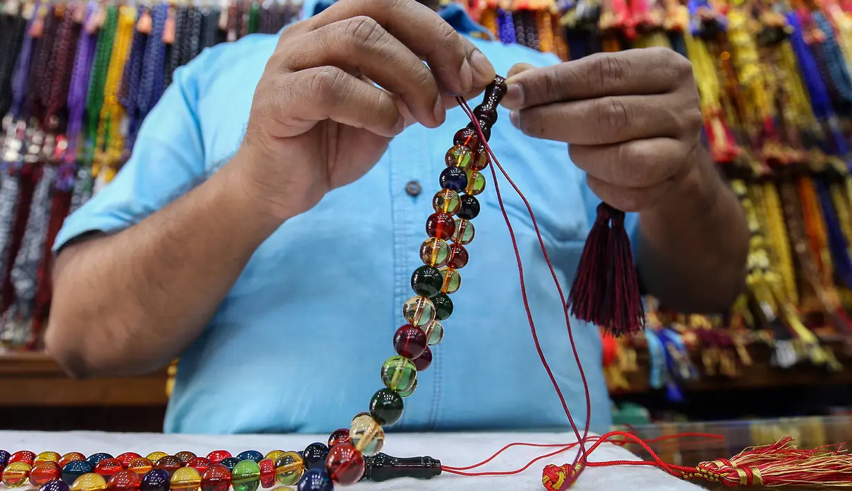Seorang pedagang saat membuat tasbih untuk dijual selama bulan suci Ramadan di sebuah pasar di Kota Kuwait (25/5/2019). Umat Muslim di seluruh dunia tengah melaksanakan puasa dimana mereka tidak makan, minum mulai dari matahari terbit hingga terbenam. (AFP Photo/Yasser Al-Zayyat)