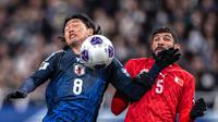 Duel antara Takumi Minamino dan Hamad Al-Shamsan pada pertandingan Timnas Jepang Vs Timnas Bahrain dalam laga ketujuh Grup C putaran ketiga Kualifikasi Piala Dunia 2026 di Stadion Saitama, Kamis (20/3/2025) (AFP/Philip Fong).