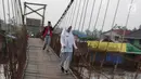 Dua orang pelajar melintasi jembatan penyeberangan di Sungai Martapura, Banjarmasin, Kalimantan Selatan, Selasa (27/3). (Liputan6.com/Immanuel Antonius)
