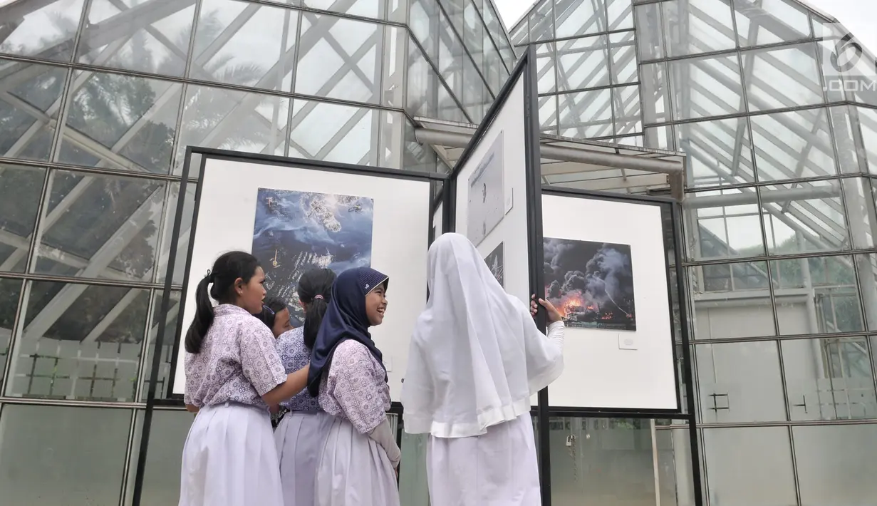 Siswa SD Negeri Menteng 01 mengamati karya foto yang dipamerkan dalam pameran fotografi Rekam Jakarta di Taman Menteng, Kamis (29/8/2019). Kegiatan tersebut dalam rangka edukasi bagi siswa mengenal profesi foto jurnalistik. (merdeka.com/Iqbal S Nugroho)
