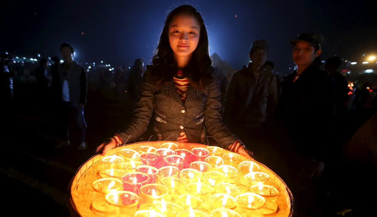 Seorang wanita membawa lilin untuk penerangan lentera kertas buatan tradisional selama festival balon Tazaungdaing tahunan di Taunggyi, Myanmar (19/11). (REUTERS/Soe Zeya Tun)