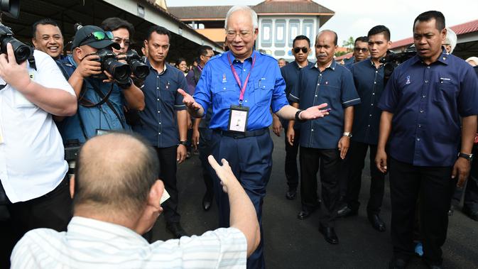 Perdana Menteri Malaysia, Najib Razak menyapa seorang pendukung di tempat pemungutan suara selama pemilihan umum di Pekan, Rabu (9/5). Pemilu ini pertarungan antara PM Najib yang sudah berkuasa sejak 2009, melawan Mahathir Mohamad. (MOHD RASFAN / AFP)