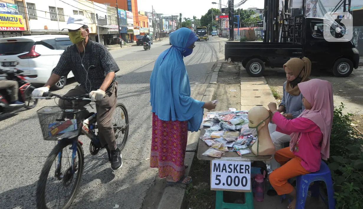 Seorang ibu ditemani anaknya melayani pembeli saat berjualan masker kain buatan rumahan di Jalan Raya Cinere-Depok, Limo, Depok, Rabu (8/4/2020). Dalam sehari ia  mampu menjual rata-rata 300 masker kain. (merdeka.com/Arie Basuki)