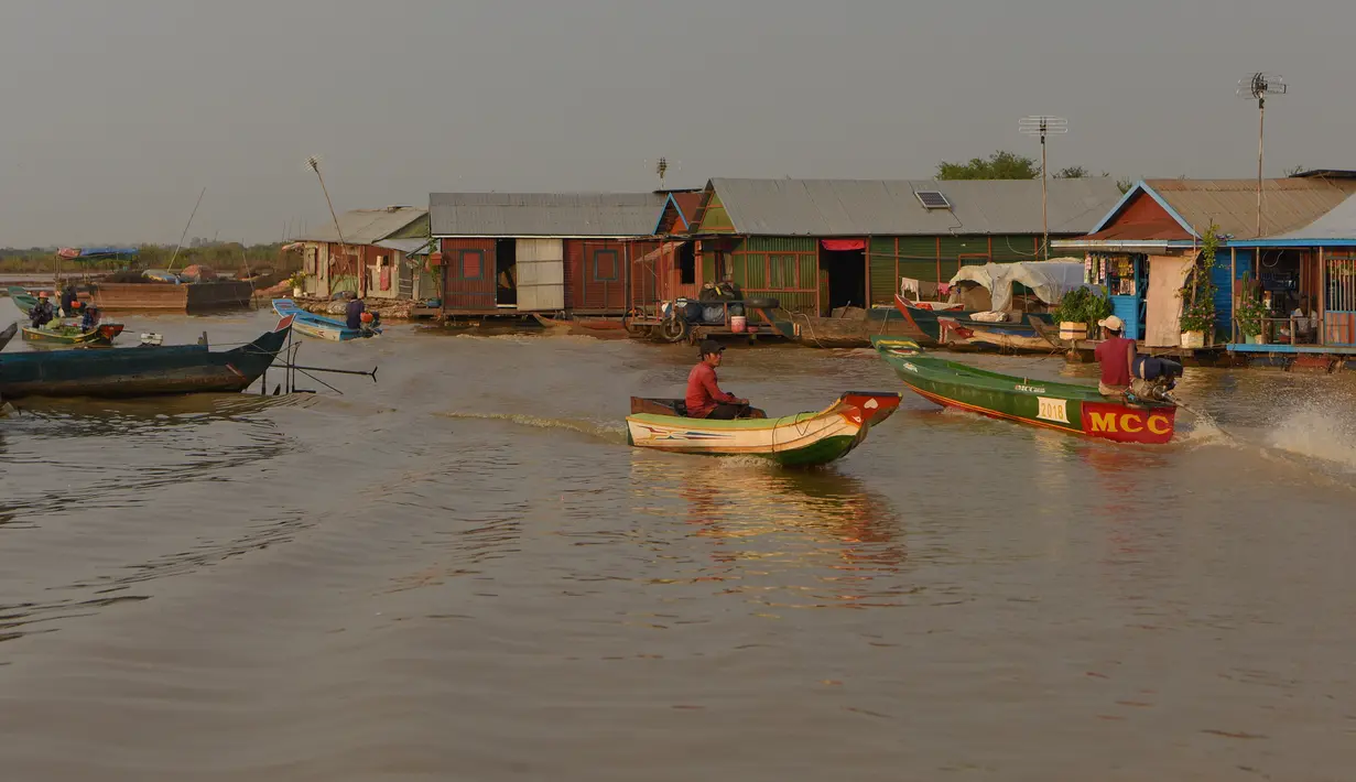 Orang-orang mengendarai perahu mereka di sungai Siem Reap di Siem Reap, Kamboja (5/12/2019). Sungai ini dikelilingi oleh sawah yang subur, bunga teratai, dan hutan banjir. (AFP/Manan Vatsyayana)