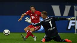Striker Bayern Munchen, Robert Lewandowski, berusaha menaklukkan kiper Schalke 04, Ralf Faehrmann, dalam lanjutan Bundesliga di Veltins Arena, Gelsenkirchen, Sabtu (10/9/2016) dini hari WIB. (AFP/Patrik Stollarz)