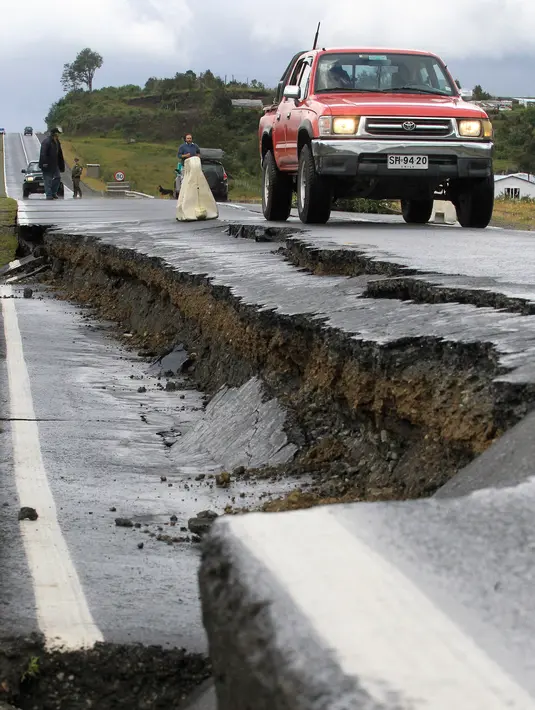 Sebuah mobil melintasi jalan yang rusak usai gempa di Pulau Chiloe, Chili, Minggu (25/12). Gempa berkekuatan 7,6 SR sempat membuat pemerintah setempat mengeluarkan peringatan tsunami. ( REUTERS / Stringer )