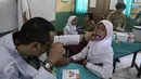 Dokter memeriksa seorang anak saat mengikuti Bulan Imunisasi Anak sekolah (BIAS) di SDN 11 Pagi, Lubang Buaya, Jakarta, Selasa (4/10). Kegiatan ini untuk mewujudkan Indonesia bebas dari kanker serviks. (Liputan6.com/Faizal Fanani)