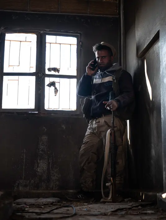 Anggota Syrian Democratic Forces (SDF) mengintai militan ISIS dari sebuah bangunan di kantong terakhir kekhalifahan di Baghouz, Suriah, Senin (18/2). ISIS menggunakan ribuan warga sipil sebagai perisai manusia. (AP Photo/Felipe Dana)