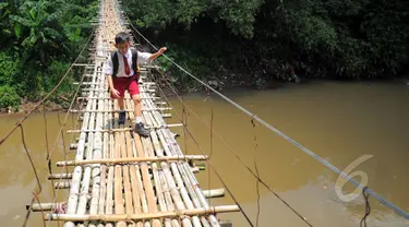 Seorang siswa SD melintas di atas jembatan gantung di atas kali Ciliwung untuk menuju ke sekolah, Jakarta, Selasa (17/3/2015). Jembatan tersebut menghubungkan Kelapa Dua Depok dengan Lenteng Agung (Liputan6.com/Yoppy Renato)