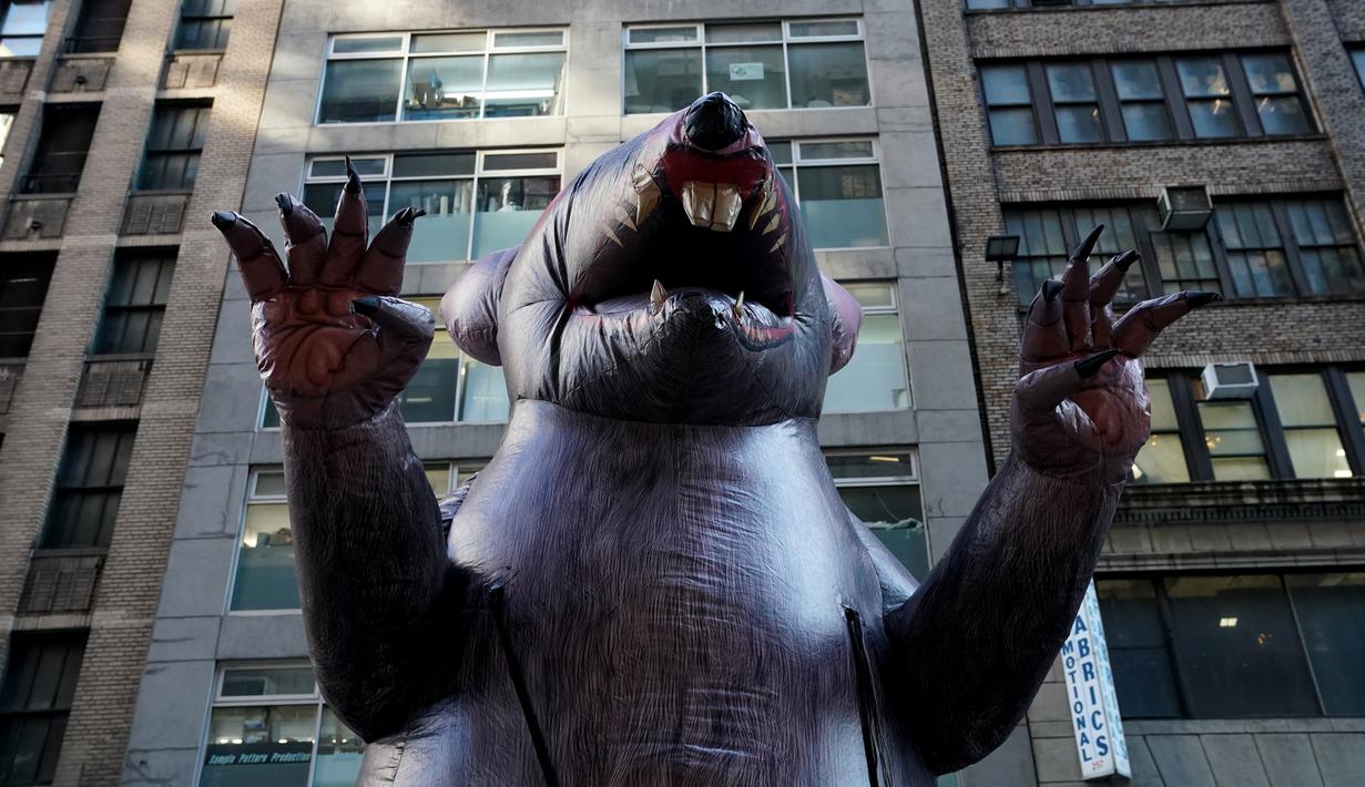 Balon tikus raksasa berjalan di tengah kota untuk diletakkan di luar kantor perusahaan di New York, Kamis (26/12/2019). Balon tikus itu sengaja ditempatkan di luar kantor sebuah pengembang di Manhattan yang dituduh tidak membayar upah pekerja bangunan non-serikat. (TIMOTHY A. CLARY/AFP)