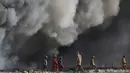 Para pekerja melihat kepulan asap kilang minyak yang dibakar oleh ISIS di Qayyara, selatan Mosul, Irak, (23/11). Sebelumnya, sekitar enam sumur minyak telah dibakar ISIS di kawasan tersebut. (REUTERS/Goran Tomasevic)