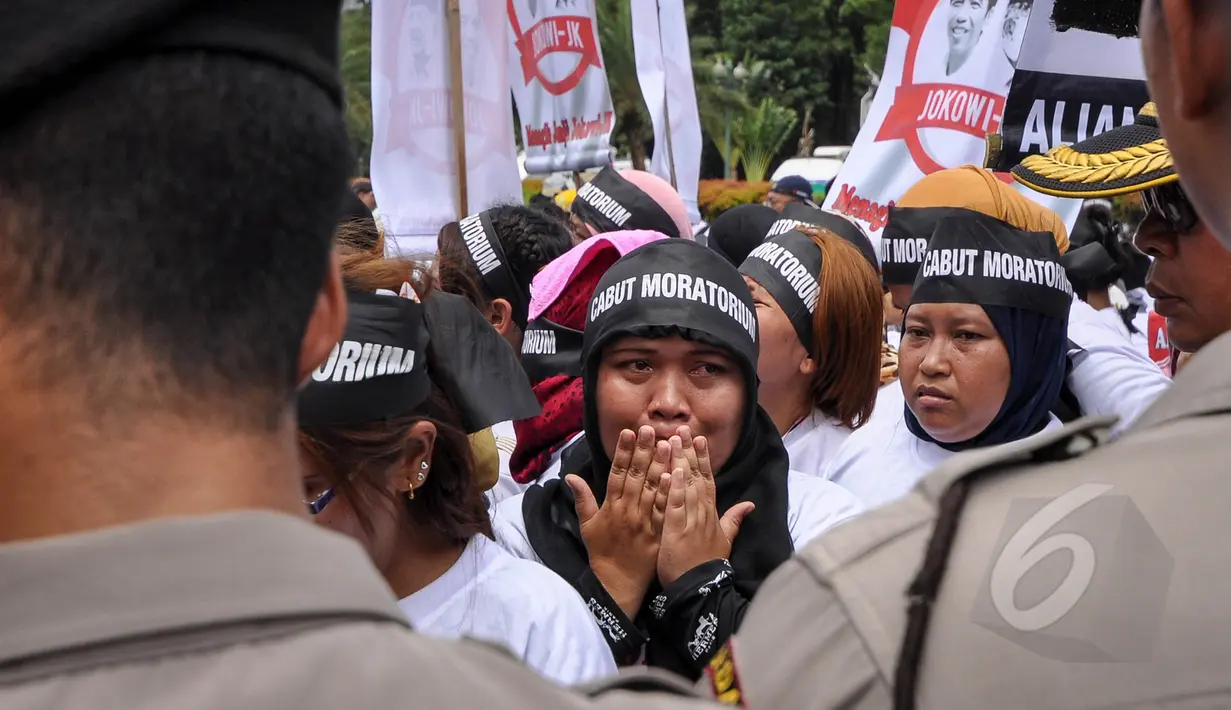 Salah satu massa tampak menangis saat menggelar aksi unjuk rasa di depan Istana Merdeka, Jakarta, Selasa (7/4/2015). Mereka menagih janji Presiden Jokowi mencabut moratorium terkait larangan pengiriman TKI ke Timur Tengah. (Liputan6.com/Faizal Fanani)