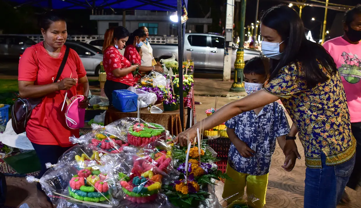 Seorang wanita dan anak-anak membeli lentera mengambang untuk dilepaskan ke sungai selama festival Loy Krathong di provinsi Narathiwat, Thailand selatan (8/11/2022). (AFP/Madaree Tohlala)