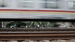 Kereta melintas saat anak-anak bermain di rel kereta api kawasan Jakarta Timur, Kamis (3/1). Minimnya lahan terbuka hijau memaksa anak-anak setempat memilih kawasan rel kereta api sebagai lokasi bermain. (Merdeka.com/Iqbal Nugroho)
