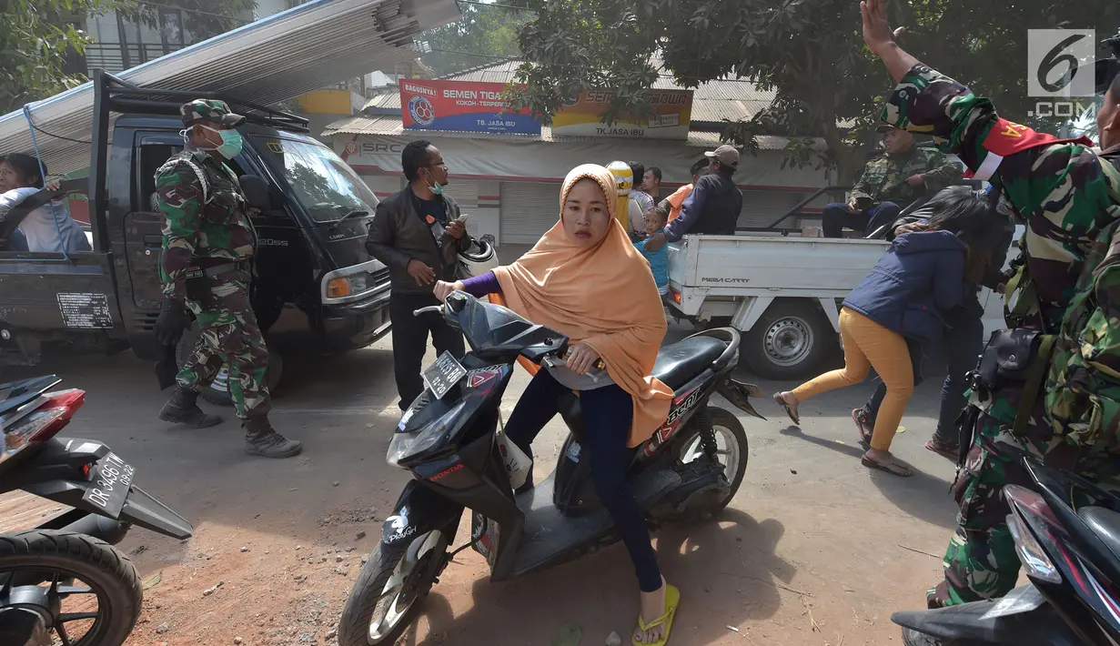 Seorang wanita menggunakan sepedah motor menyelamatkan diri saat terjadi gempa susulan di Tanjung pulau Lombok, NTB, Kamis (9/8).Gempa susulan tersebut menyebabkan kepanikan di antara pengungsi yang berlindung.(AFP/ ADEK BERRY)