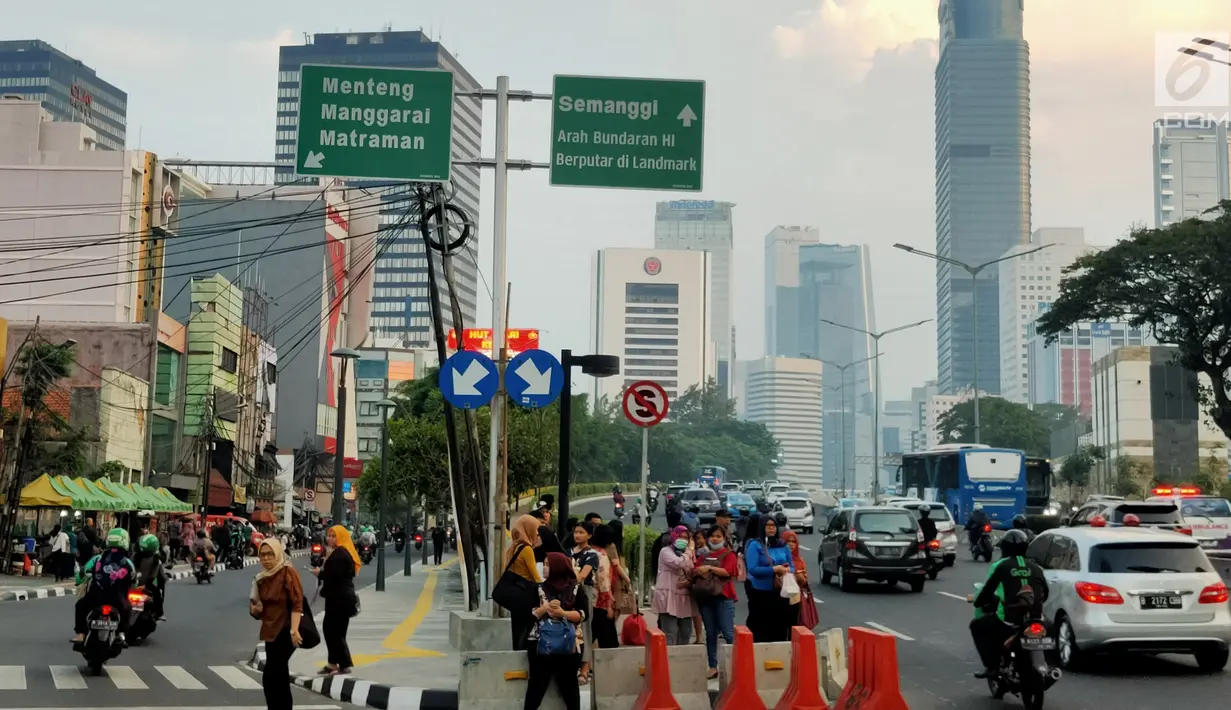 Warga menunggu angkutan umum di tepi Jalan Jenderal Sudirman, Jakarta, Senin (8/7/2019). Tidak adanya halte tersebut mengurangi kenyamanan serta mengganggu arus lalu lintas. (Liputan6.com/Immanuel Antonius)