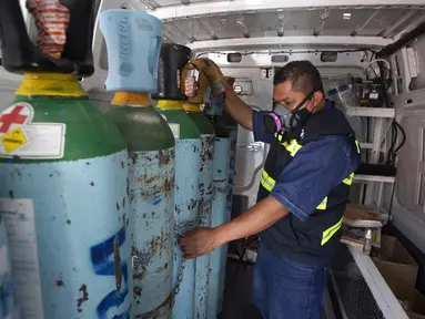 Petugas kesehatan Jose Antonio Pena mengisi ulang tangki oksigen untuk pasien COVID-19 di Distrik Iztapalapa, Mexico City, Meksiko, Selasa (26/1/2021). Mexico City menawarkan isi ulang oksigen gratis untuk pasien COVID-19. (AP Photo/Marco Ugarte)