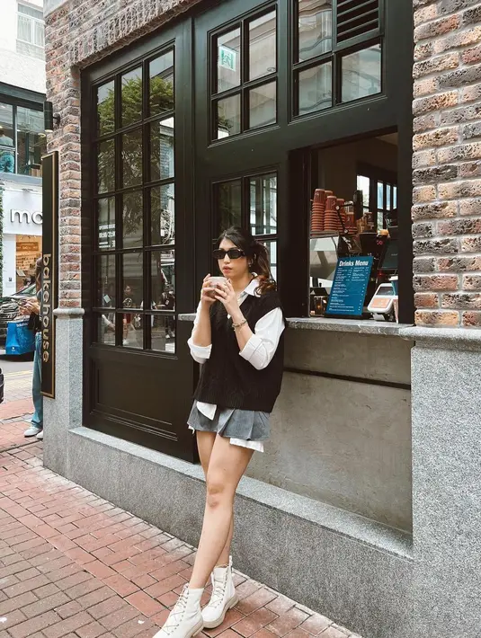 Penampilan chic lainnya dari Mici pakai kemeja putih yang ditumpuknya dengan knitted vest hitam dan mini skirt abu-abu. [Foto: Instagram/parramitha]