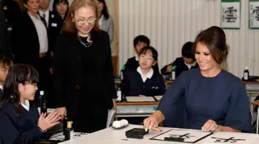 Ibu Negara AS Melania Trump bersiap menulis huruf kanji dengan bantuan siswa saat menghadiri kelas kaligrafi di sekolah dasar Kyobashi Tsukiji, Tokyo (6/11). Melania menulis karakter kaligrafi China dengan arti "Damai". (AFP Photo/Pool/Toshifumi Kitamura)
