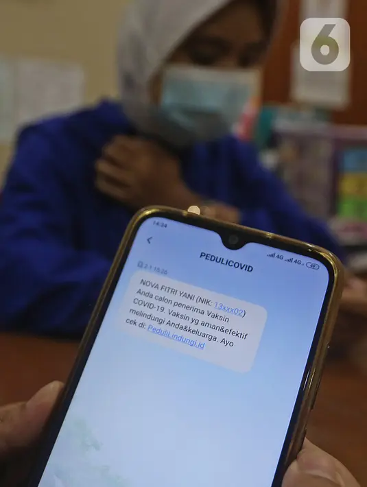 Tenaga kesehatan membaca pesan singkat penerima vaksin COVID-19 di RSIA Tambak, Jakarta, Selasa (5/01/2021). Kementerian Kesehatan mengirimkan Short Message Service (SMS) blast secara serentak kepada penerima vaksin COVID-19 tahap pertama pada Kamis (31/12) lalu. (Liputan6.com/Herman Zakharia)