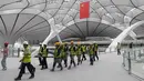 Para pekerja berjalan dalam Terminal Bandara Internasional Daxing Beijing, China, Selasa (9/7/2019). Bandara yang selesai pada 30 Juni 2019 tersebut dijadwalkan dibuka pada 30 September 2019. (GREG BAKER/AFP)