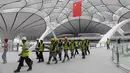 Para pekerja berjalan dalam Terminal Bandara Internasional Daxing Beijing, China, Selasa (9/7/2019). Bandara yang selesai pada 30 Juni 2019 tersebut dijadwalkan dibuka pada 30 September 2019. (GREG BAKER/AFP)