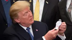 Presiden AS, Donald Trump memegang mainan Astronot setelah menandatangani sebuah kebijakan untuk mengirim astronot Amerika kembali ke bulan dan Mars di Ruang Roosevelt Gedung Putih di Washington (11/12). (AFP/Saul Loeb)