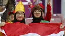 Dua suporter wanita Indonesia membentangkan bendera Merah Putih di tribun stadion sebelum dimulainya laga kedua Grup D Piala Asia 2023 antara Timnas Indonesia menghadapi Vietnam di Abdullah Bin Khalifa Stadium, Doha, Qatar, Jumat (19/1/2024). (AFP/Karim Jaafar)