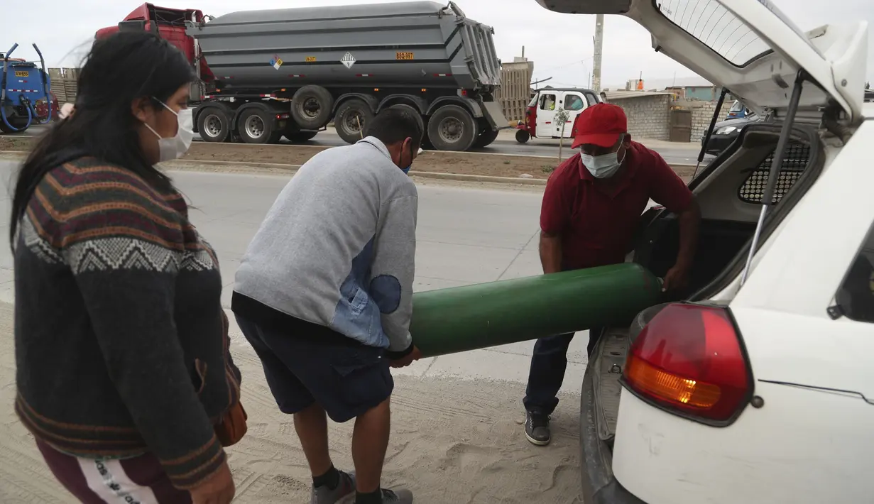 Orang-orang membawa tabung oksigen kosong dari mobil ke toko untuk mengisinya kembali di tengah pandemi COVID-19 di kawasan kumuh Villa El Salvador di Lima, Peru, Kamis (21/1/2021). Toko dibatasi untuk mengisi ulang hanya 20 tabung oksigen dalam sehari. (AP Photo/Martin Mejia)