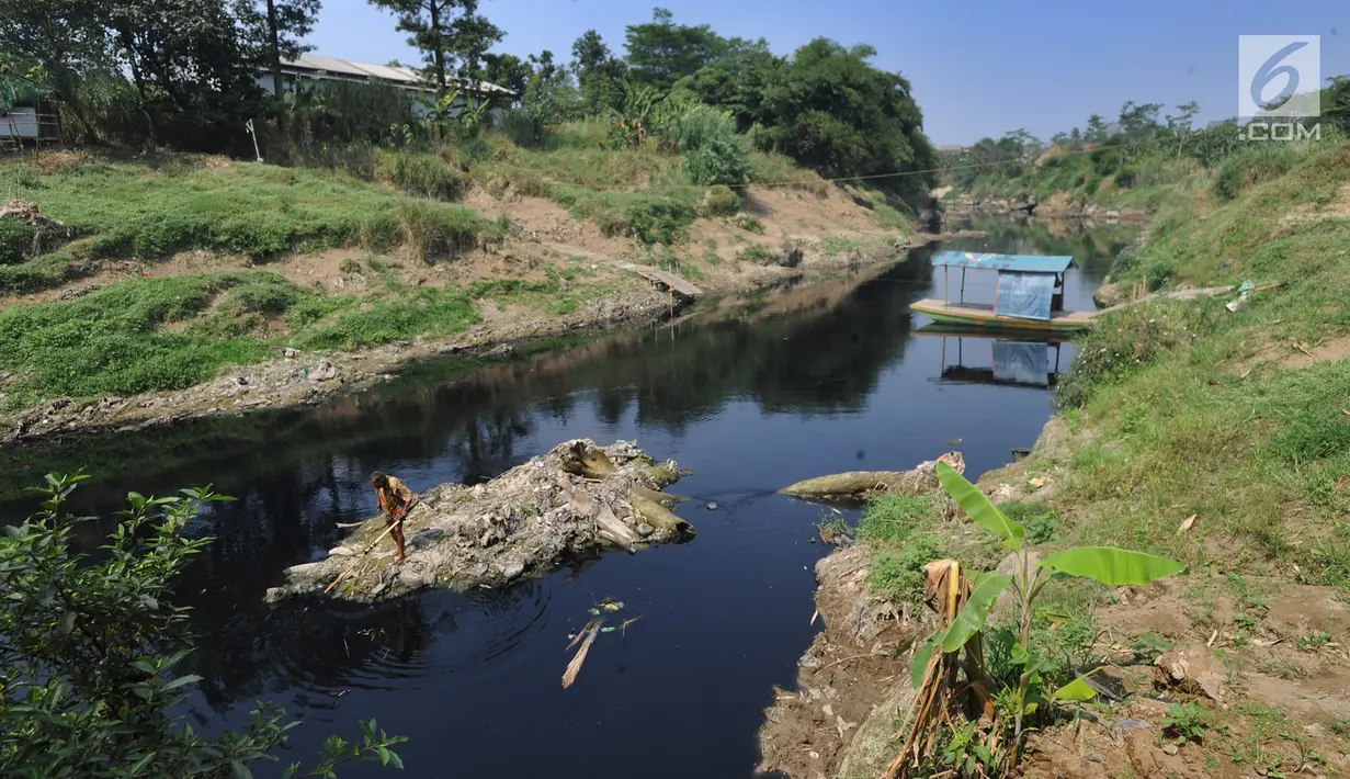 Warga mencari ikan di aliran Sungai Cileungsi yang berwarna hitam pekat di kawasan Bojong Kulur, Gunung Putri, Kabupaten Bogor, Jawa Barat, Selasa (23/7/2019). Air Sungai Cileungsi berubah warna menjadi hitam diduga akibat pencemaran limbah pabrik di kawasan tersebut. (merdeka.com/Arie Basuki)