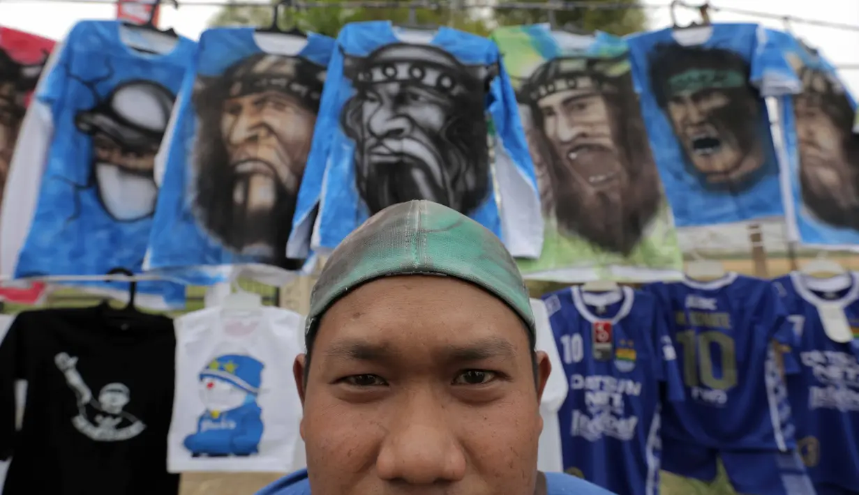 Seorang pedagang atribut merapikan dagangan berupa Jersey dari airbrush di Stadion Si Jalak Harupat, Bandung, Sabtu (24/10/2015). (Bola.com / Nicklas Hanoatubun)