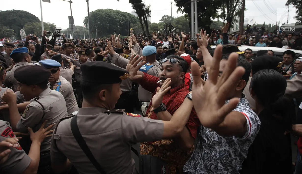 Demonstran driver online saling dorong dengan polisi saat unjuk rasa di depan Istana Negara, Jakarta, Rabu (14/2). Aksi pemberhentian mobil taksi online yang masih beroperasi oleh demonstran sempat membuat situasi tegang. (Liputan6.com/Arya Manggala)