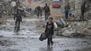 Seorang anak perempuan membawa dua ember kosong saat berjalan menuju tempat mengambil air di tengah hujan deras di kawasan Sheikh Radwan, Kota Gaza, Jumat 14 November 2025. Anak-anak di Gaza masih mengalami kekurangan air bersih. (AP Photo/Jehad Alshrafi)