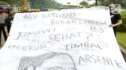 Sejumlah aktivis melakukan aksi simbolik di kawasan Patung Kuda, Jakarta, Kamis (18/3/2021). Aktivis menuntut Presiden Joko Widodo untuk mencabut Omnibus Law UU Cipta Kerja dan regulasi turunannya yang menghapus Fly Ash Bottom Ash (FABA) dari daftar limbah B3. (Liputan6.com/Faizal Fanani)