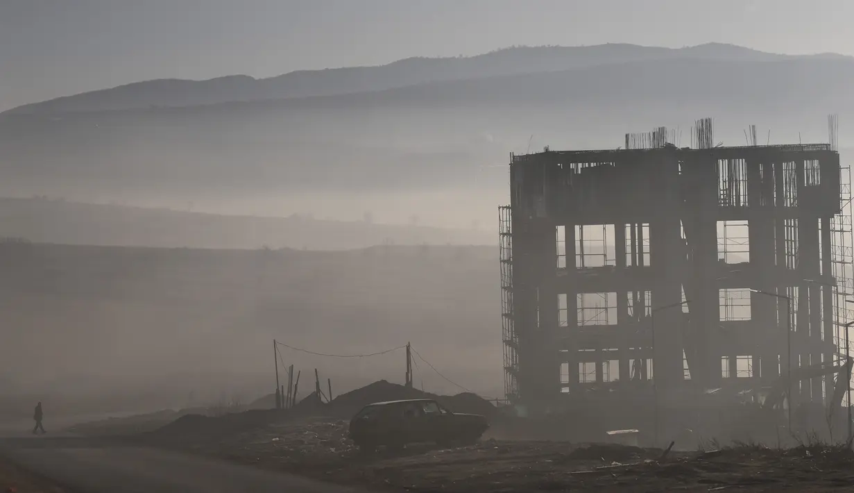 Seorang pria berjalan saat kabut tebal melanda kota Pristina (17/12/2019). Pristina dan banyak kota lain di Kosovo mengalami polusi udara tingkat tinggi. (AFP/Armend Nimani)
