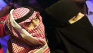 Seorang pria Saudi menggunakan keffiyeh tradisionalnya sebagai masker ketika ia menyaksikan pertandingan gulat WWE Super ShowDown di Riyadh, Arab Saudi, Kamis (27/2/2020). Arab Saudi menghentikan sementara izin umrah karena kekhawatiran tentang epidemi virus corona COVID-19. (AP Photo/Amr Nabil)