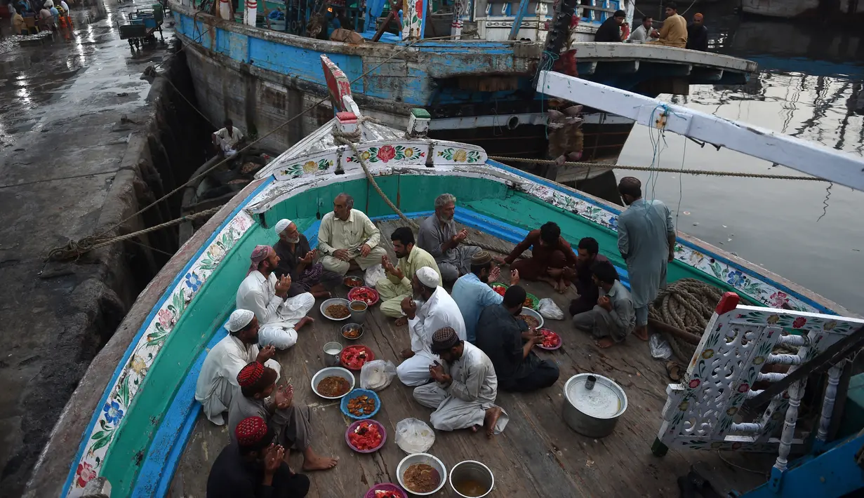 Nelayan duduk di atas kapal saat mereka berdoa sebelum berbuka puasa selama bulan suci Ramadhan di galangan kapal di kota pelabuhan Karachi, Pakistan pada 18 April 2022. Setelah menjalani ibadah puasa, waktu buka puasa menjadi momen yang dinanti oleh umat Islam. (Rizwan TABASSUM / AFP)