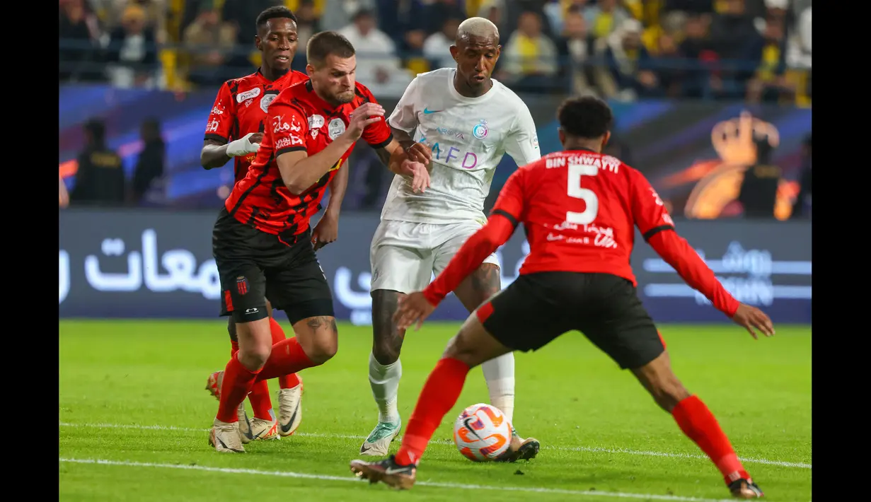 Pemain Al Nassr, Talisca (tengah), mengontrol bola dibayangi dua pemain Al Riyadh dalam laga pekan ke-16 Saudi Pro League 2023/2024 yang digelar di Al Awwal Park, Sabtu (9/12/2023) dini hari WIB. Dalam pertandingan tersebut Talisca memborong dua gol dari kemanangan 4-1 atas Al Riyadh. (AFP/Fayez Nureldine)
