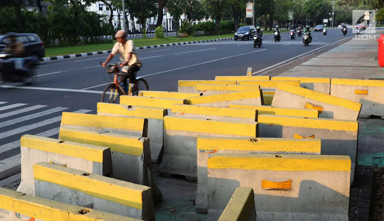 Pejalan kaki menghindari beton pembatas jalan yang diletakkan di atas trotoar Jalan Medan Merdeka Utara, Jakarta, Kamis (25/7/2019). Pembatas jalan yang berada tidak pada tempatnya mengganggu kenyamanan pejalan kaki yang melintasi trotoar jalan tersebut. (Liputan6.com/Helmi Fithriansyah)