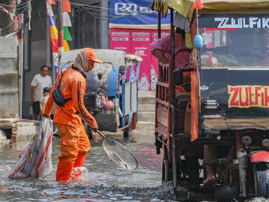 Petugas Penanganan Prasarana dan Sarana Umum (PPSU) membersihkan sampah pada genangan air rob yang melanda wilayah Muara Angke, Jakarta Utara, Selasa (19/11/2024). (merdeka.com/Arie Basuki)