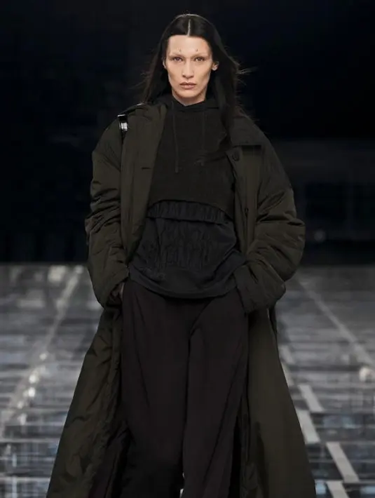 Ini potret Bella Hadid memamerkan koleksi Givenchy 2022. Dia terlihat chic memadukan hoodie dengan long coat dan baggy pants warna cokelat. (Dok/GIVENCHY).