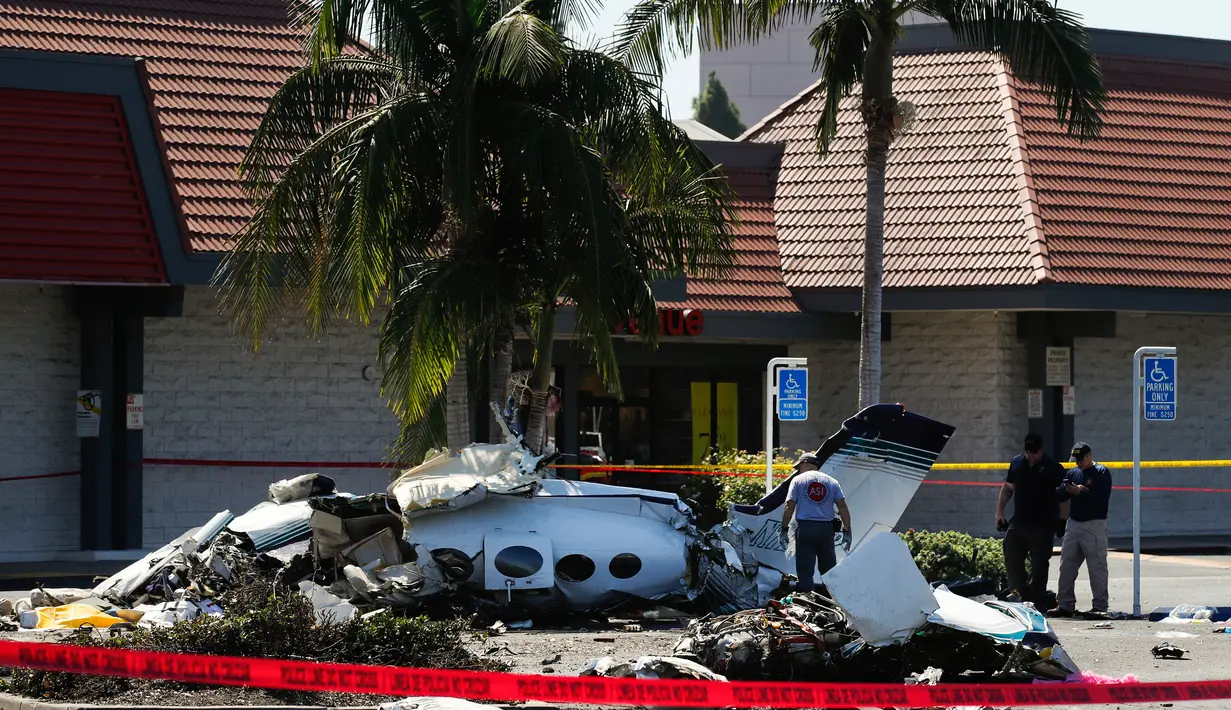 Tim investigasi menyelidiki reruntuhan sebuah pesawat kecil yang jatuh ke area parkir pusat perbelanjaan di Santa Ana, California, Senin (6/8). Dalam insiden itu, sebanyak lima orang penumpang pesawat meninggal dunia. (AP/Jae C. Hong)