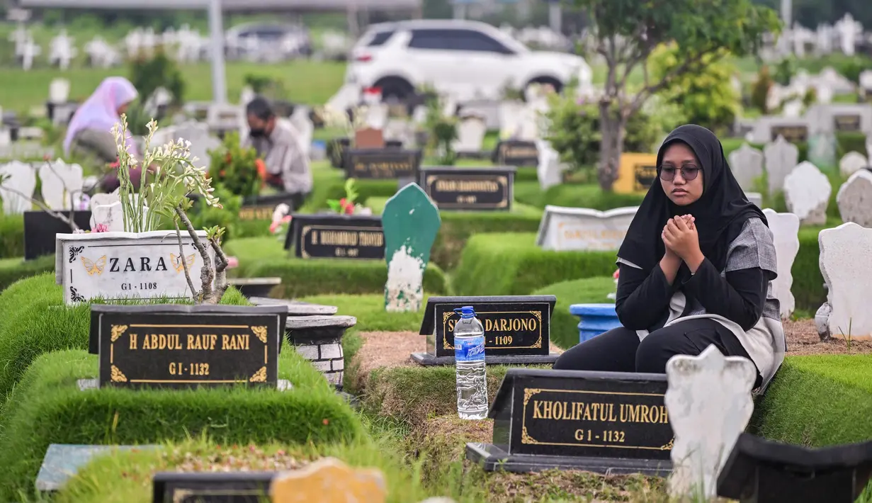 Suasana haru terlihat saat peziarah memanjatkan doa di sisi pusara makam keluarga. (JUNI KRISWANTO/AFP)