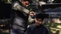 Tukang cukur muda di pengungsian korban gempa Turki. (dok. Sameer Al-DOUMY / AFP)