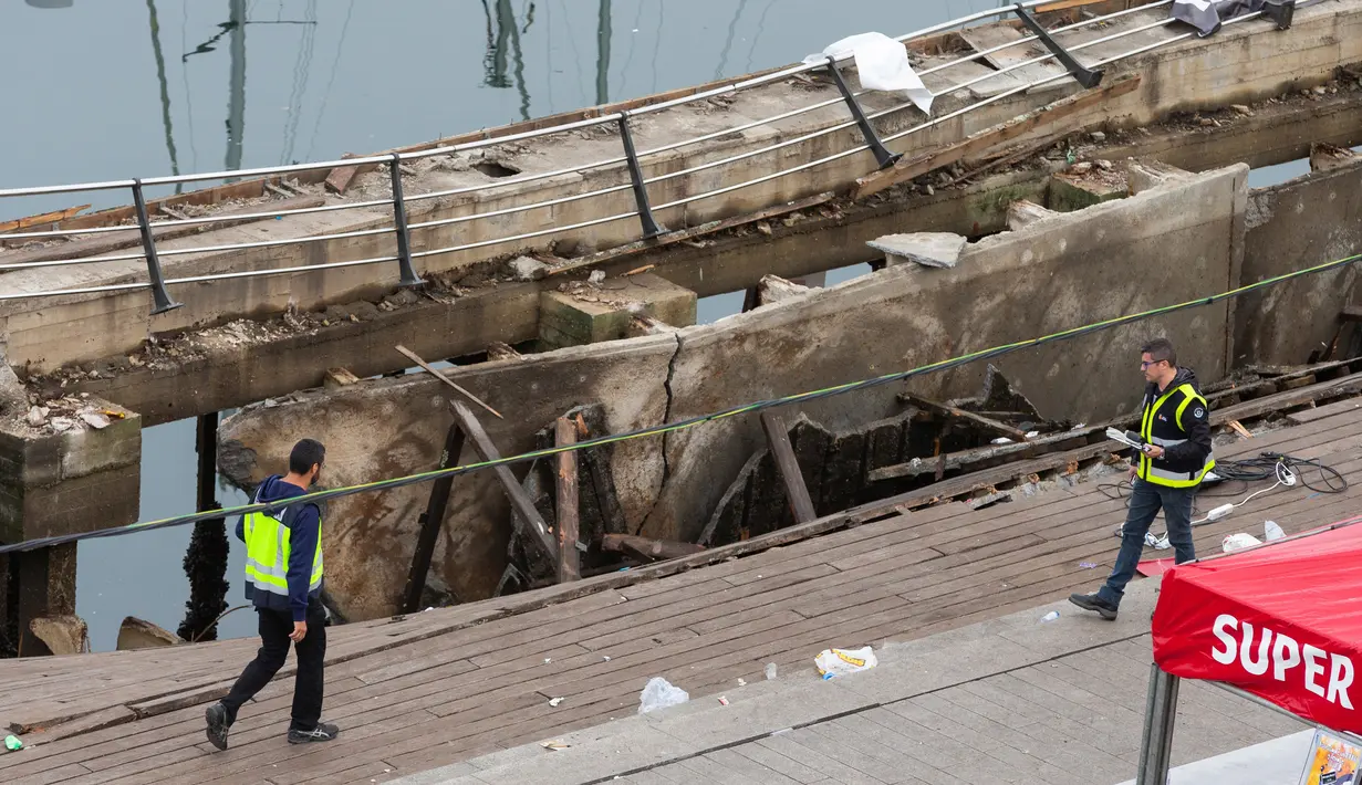 Petugas kepolisian berjalan di lokasi robohnya platform panggung dari kayu pada festival musik di tepi laut di Vigo, Spanyol, Senin (13/8). Festival musik di Spanyol itu bernama 'O Marisquino' dan berlangsung selama dua hari. (12/8). (AP/Lalo R. Villar)